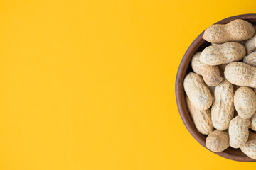 Fresh organic peanuts in the bowl on yellow background
