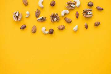 nuts mix for a healthy diet cashew, peanut, hazelnuts, walnuts, almonds on yellow background
