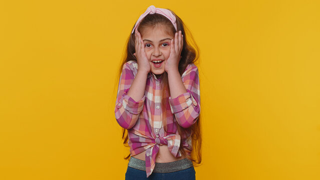 Oh My God, Wow. Young Preteen Child Girl Kid Looking Surprised At Camera With Big Eyes, Shocked By Sudden Victory, Game Winning Lottery Goal Achievemen Good News. Toddler Children On Yellow Background