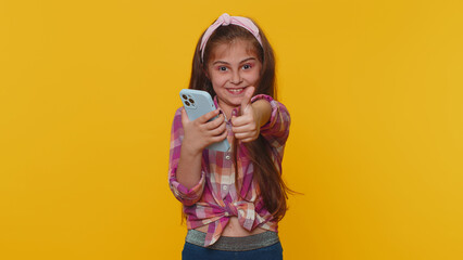 Young preteen child girl kid texting share messages content on smartphone social media applications online, watching relax movie, show thumbs up like, positive feedback. Little one toddler children