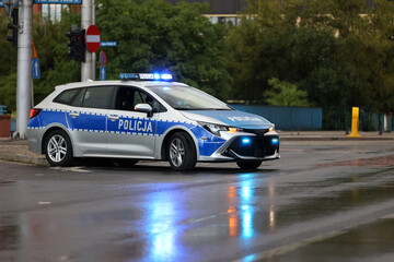 Radiowóz polska policja wieczorem z sygnalizatorem  błyskowy niebieski na dachu. Nocny patrol.  - obrazy, fototapety, plakaty