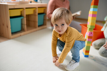 Small boy enjoys in playing with toy block at daycare.