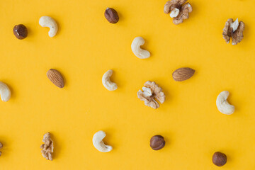 Organic mixed nuts on yellow background, top view