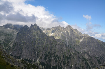 Obraz premium View to sharp rocky peaks covered low clouds of High Tatras mountains in Slovakia in summer. Trail to mount Slavkovsky stit 