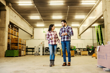 Fototapeta premium Two factory workers walking in facility and talking about business.