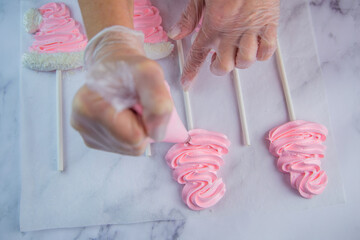 From the pastry bag, the pastry chef squeezes out a zigzag meringue on white parchment and a red...