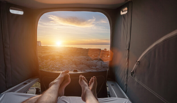 girl boy couple sleeping in mini van and looking on the ocean at summer sunset scenery
