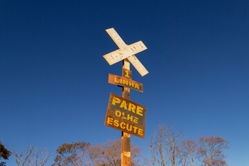Sinal de cruzamento de linha férrea com céu ao fundo.