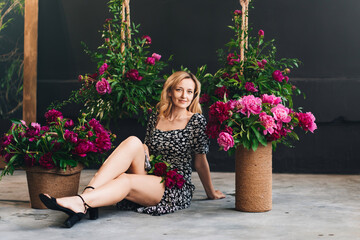 an attractive middle-aged blonde woman sits on the floor with flowers.