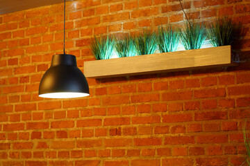 a black luminous chandelier against a brick wall with a green decor