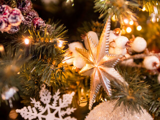 Obraz na płótnie Canvas Christmas tree with shiny decorations. Fir tree decorated with light bulbs and star for New Year celebration.