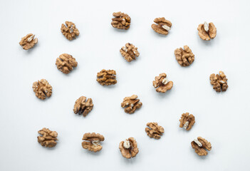Halves of walnuts on white background, pattern, top view.