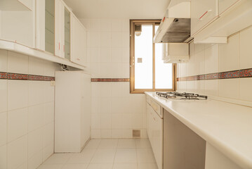 Kitchen with white furniture and details in red, countertop and appliances in the same color and border on the tiles, cabinet with glass cabinet and golden aluminum window