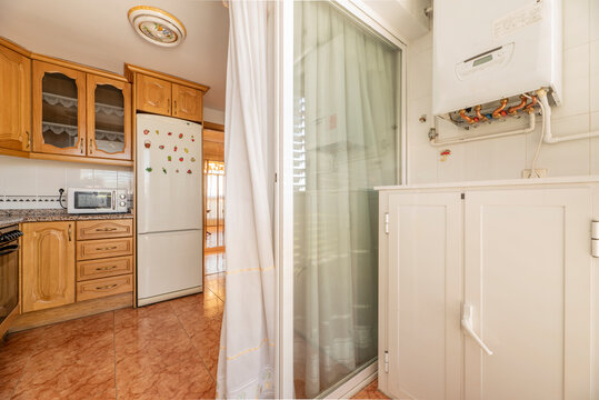 Drying Terrace Of A Kitchen With Natural Gas Water Heater, Aluminum Cabinet And Kitchen In The Background