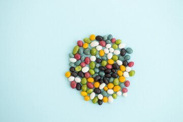 Colorful coated chocolate candies scattered on blue background