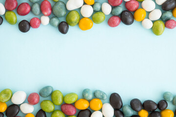 Colorful coated chocolate candies scattered on blue background