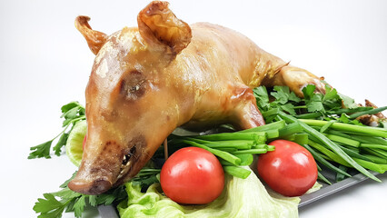 a suckling pig or pig roasted on a spit or in the oven lies on a tray. festive pork dish decorated...