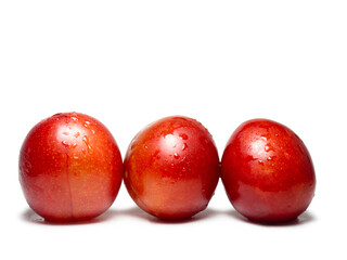 Red cherry plum in water droplets. Ripe fruit on a white background. Red plum. Ingredient for tkemali sauce.