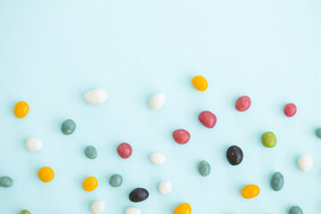 Colorful coated chocolate candies scattered on blue background