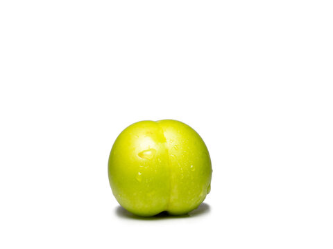 Green cherry plum in water droplets. Unripe fruit on a white background. Green plum. Ingredient for tkemali sauce.