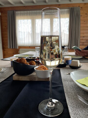 a glass of sparkling wine on the background of a set table with snacks, cheese