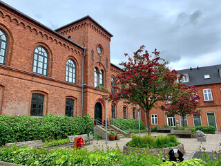 Beautiful historic red brick building of the music school in Lemvig with forecourt, red flowering...
