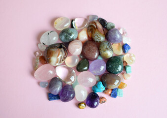 Gems of different colors. Amethyst, rose quartz, agate, apatite, aventurine, olivine, turquoise, aquamarine, rhinestone lie on a pink background. Top view