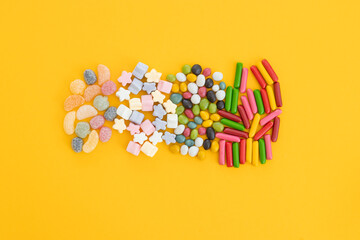 many different candies, sweets on yellow background