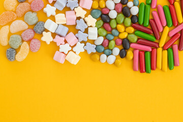 many different candies, sweets on yellow background