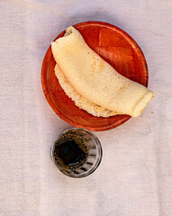 Tapioca or beiju stuffed with cheese and condensed milk, on a wooden background with a cup of coffee. Flat bread made from cassava (also known as casabe, bammy, beiju, bob, biju).