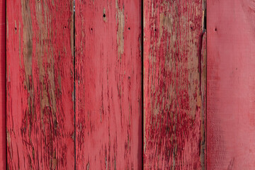 Weathered dark bright scarlet red painted vertical wooden plank wall with painted nails