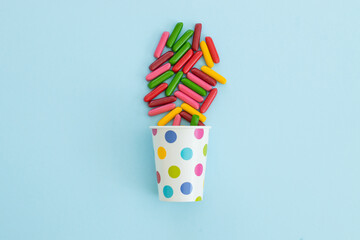 many different candies , sweets in paper cup on blue background