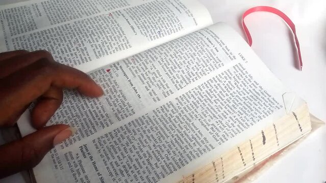 Black lady's hand looking for a bible verse in the bible with her finger. Footage. She's flipping the pages searching, Nairobi, Kenya. Christianity concept.
