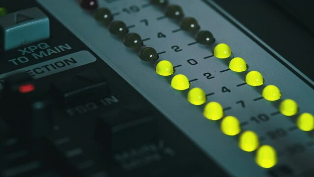 LED indicator of sound level signal on the mixing console. Close-up shot of strip in green and yellow on VU output level indicator. Volume level changes of indicator bulbs. Stereo meters on a soundbar