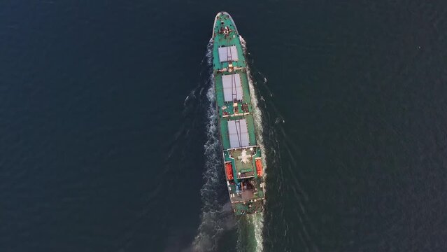 Cargo ship sails on the sea at sunset. A bulk carrier is a merchant ship designed to transport unpackaged bulk cargo (grain, ore, coal). View from the drone vertically down