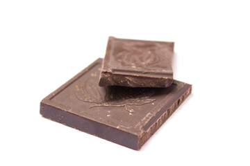 two cubes of dark chocolate lie on a white background