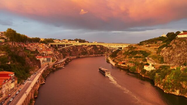 4K panoramic video of a boat cruising through the river Douro during the sunset shot from the top of Luis I Dom bridge in Porto, Portugal.