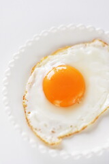 Homemade comfort food, sunny side up fried egg on white plate