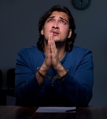 Young convict man sitting in dark room
