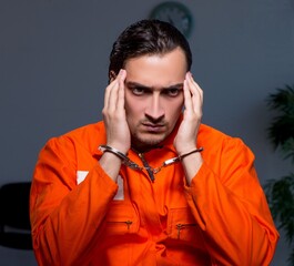 Young convict man sitting in dark room