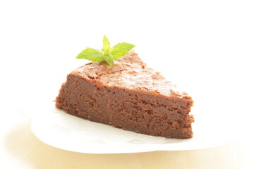 Piece of homemade chocolate cake on white dish with mint