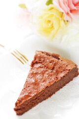 Piece of homemade chocolate cake on white dish with mint