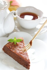 Piece of homemade chocolate cake on white dish with mint