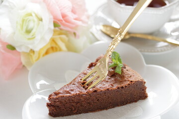 Piece of homemade chocolate cake on white dish with mint