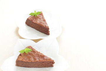 Piece of homemade chocolate cake on white dish with mint