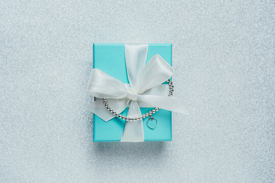 Barcelona, Spain - July 2022.. Tiffany and Co branded gift box with heart bracelet from world-famous American fashion brand. Luxury, trendy jewelry present on glitter background