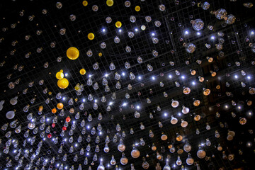 Hundreds of incandescent light bulbs suspended below a black metal grid, nobody