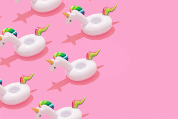 Creative art minimal aesthetic. Inflatable unicorn pool toy pattern on pastel pink background. Minimal summer concept with trendy summer shadows.