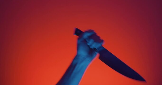 Close up of hand raising sharp knife and stabbing off camera