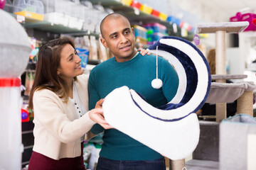 Family couple choosing accessories for cats in a pet store